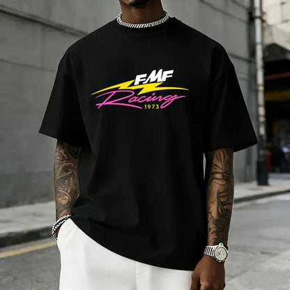 Men’s FMF Racing 1973 graphic T-shirt featuring a retro pink/yellow lightning logo print, made from a soft cotton blend—perfect for motocross fans, streetwear enthusiasts, and casual motorsport-inspired outfits.